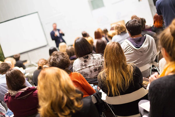A group of people sitting in front of a white board.