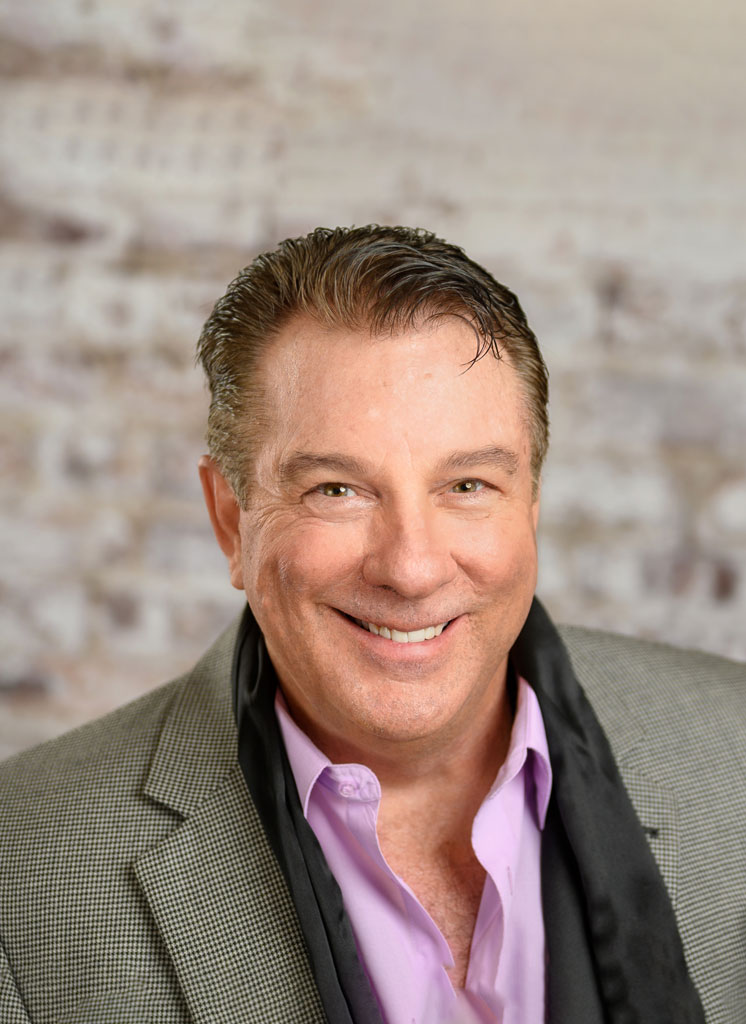 A man in a suit and tie smiling for the camera.
